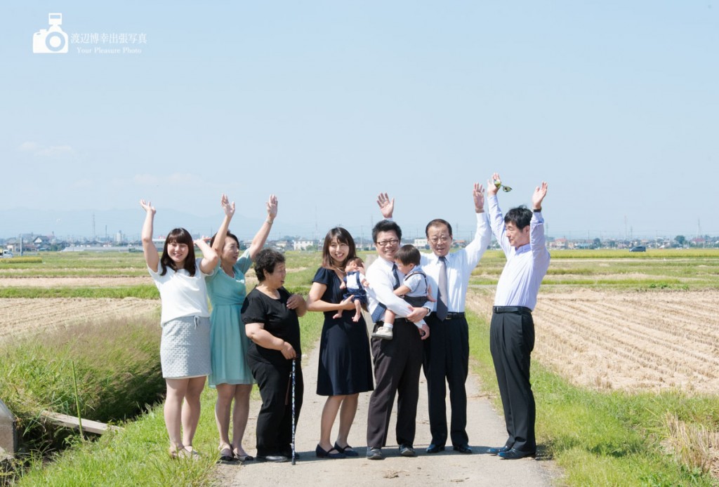 田んぼの畦道でバンザイをする複数の人達