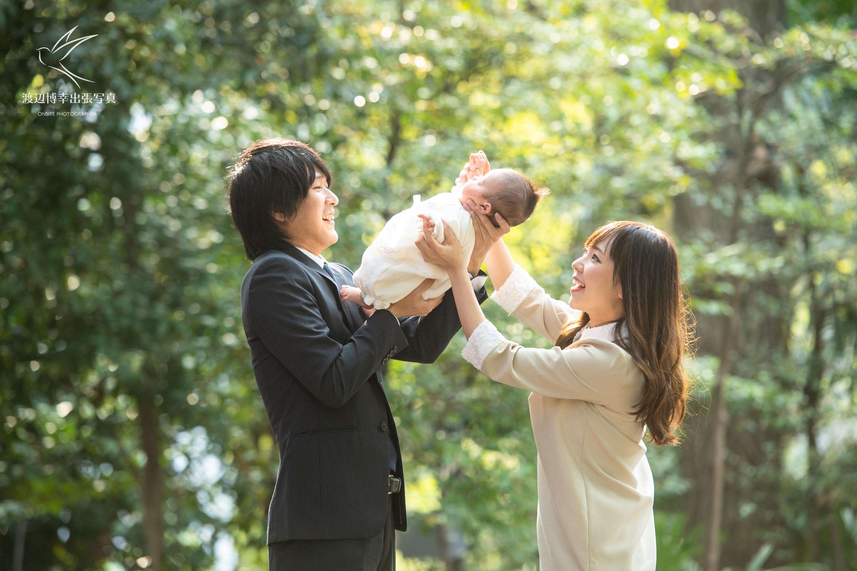 赤坂の日枝神社でお宮参りの掛着を着て赤ちゃんを抱く夫婦の写真