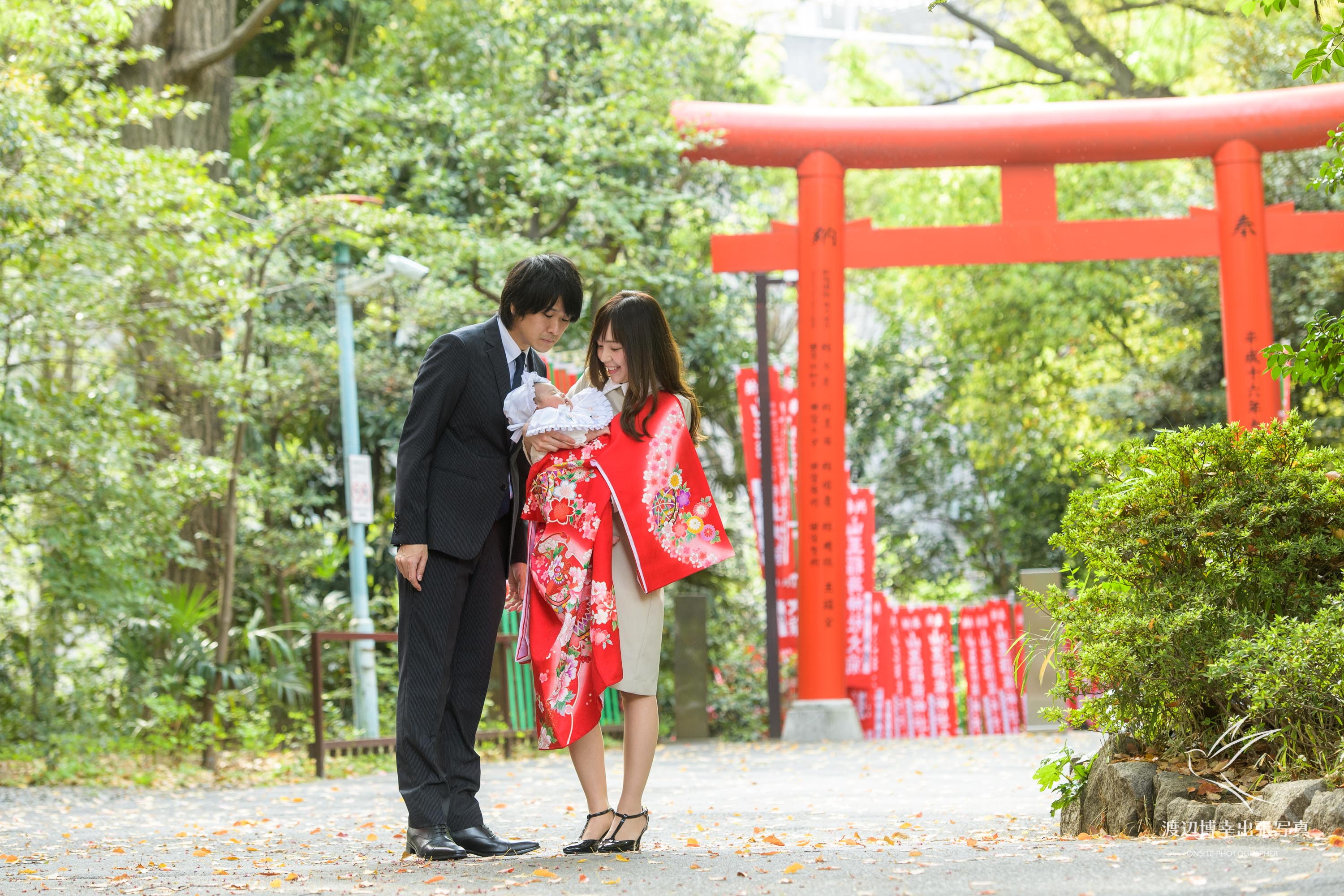 赤坂の日枝神社でお宮参りの掛着を着て赤ちゃんを抱く夫婦の写真