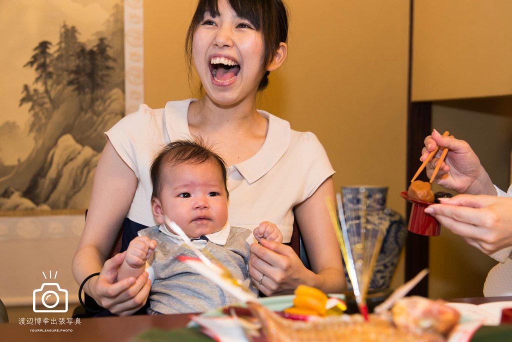 赤ちゃんを膝の上に抱き笑う女性