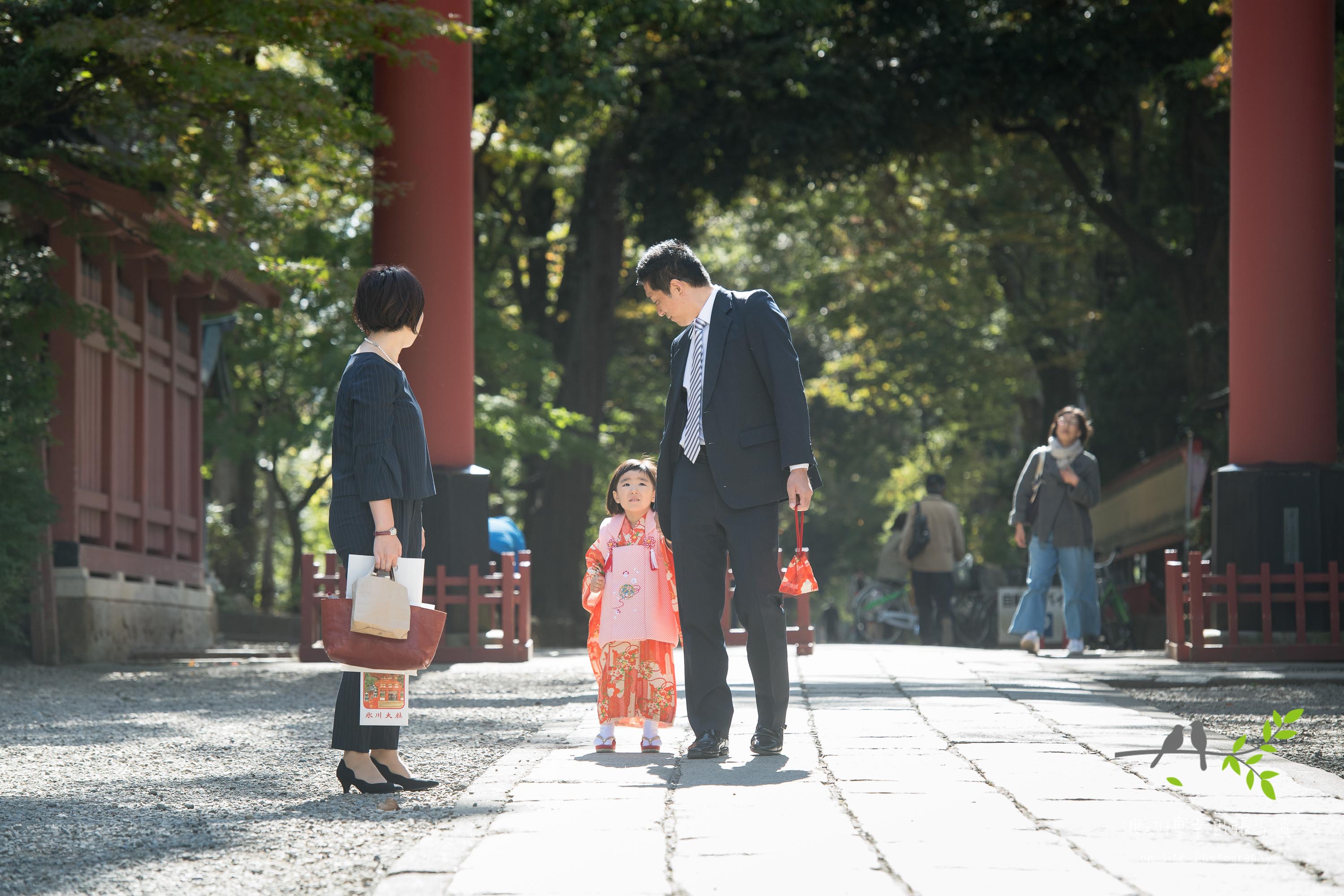 参道の上に立つ父親と母親と着物姿の小さな女の子