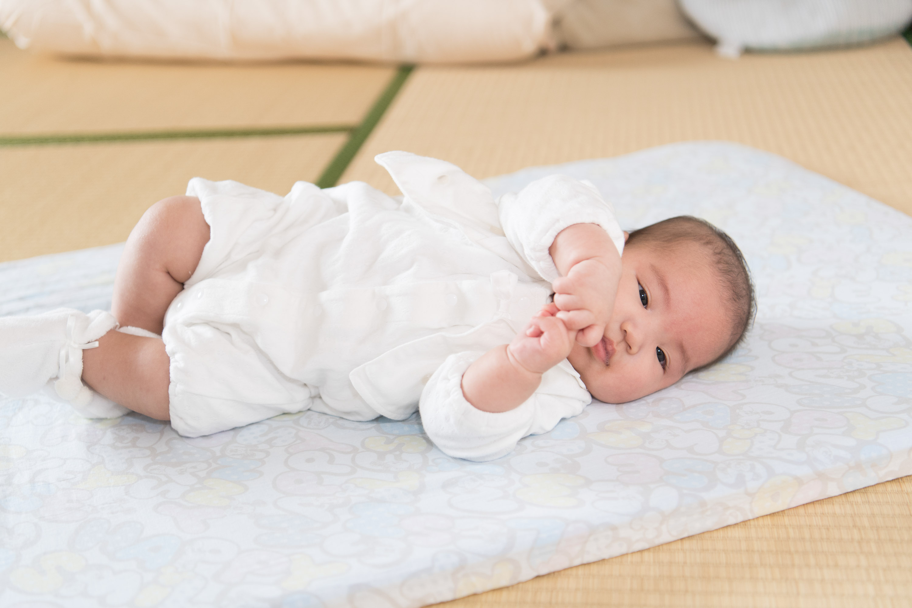 畳の部屋の小さなマットに横たわる赤ちゃん
