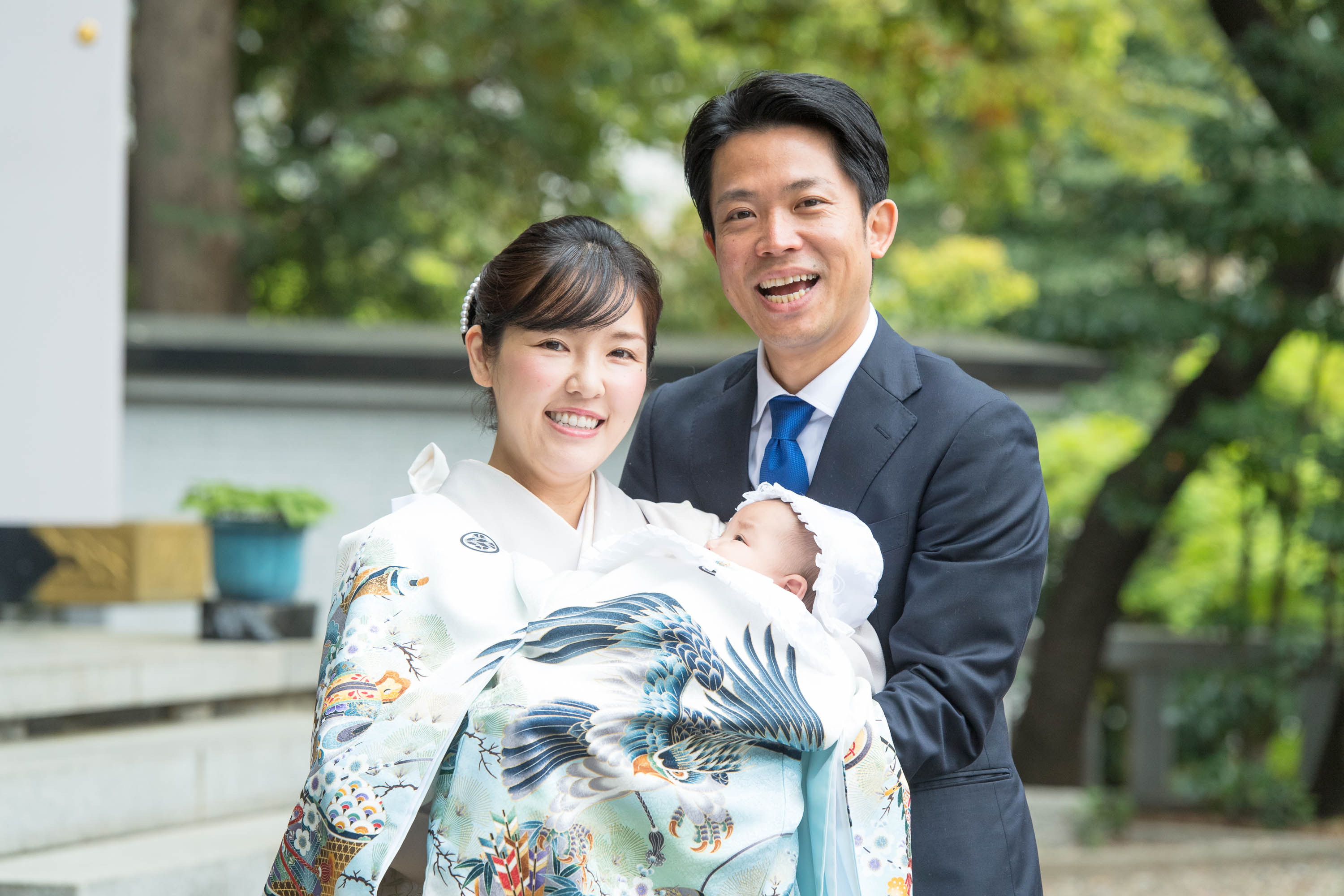 掛着姿の赤ちゃんを抱く笑顔の和装の女性と男性