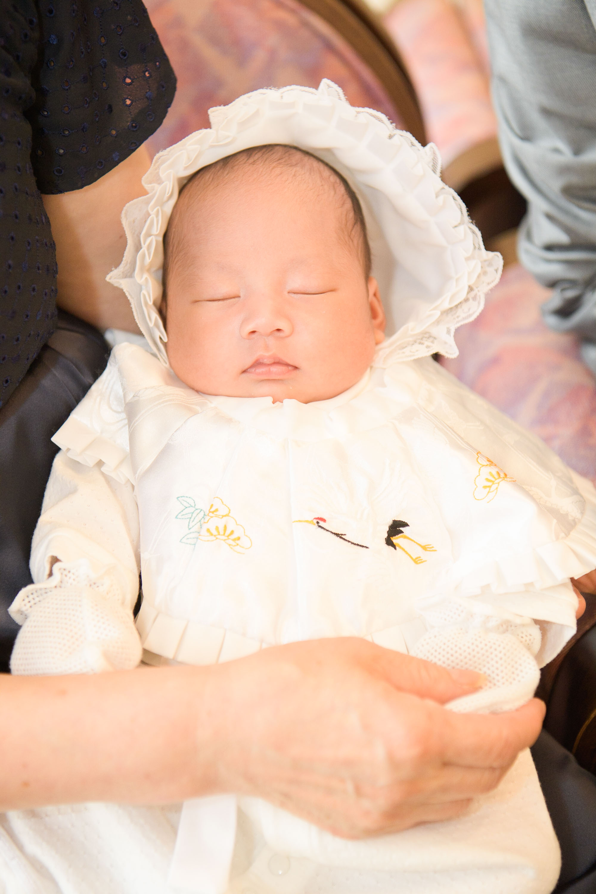 白いベビードレスに身を包んだ赤ちゃんのアップ