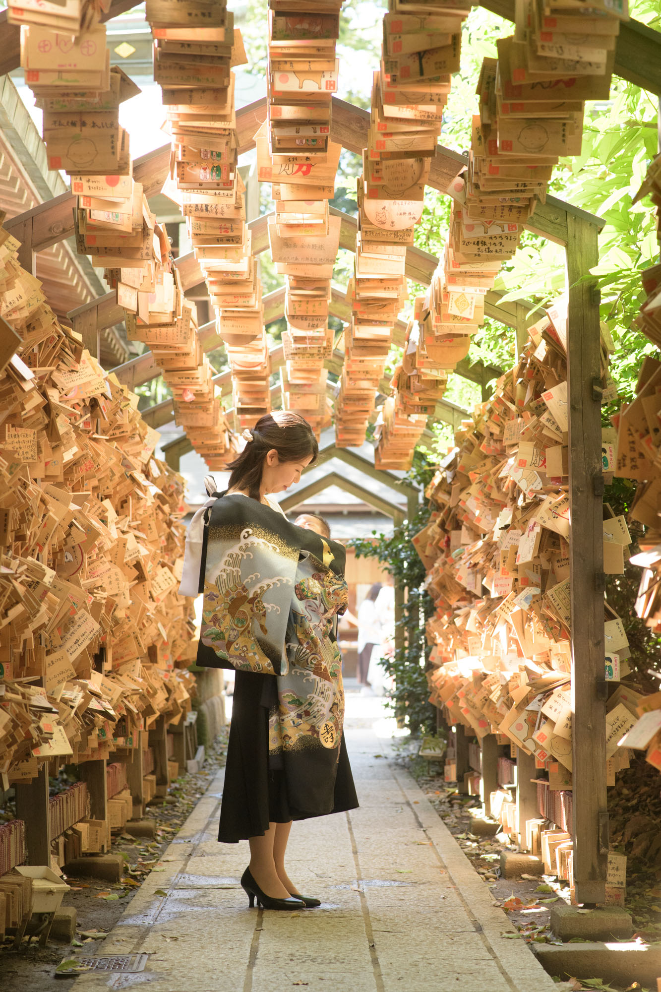 川越氷川神社のお宮参り、絵馬トンネルの中で掛け着をつけて赤ちゃんを抱っこするお母さん