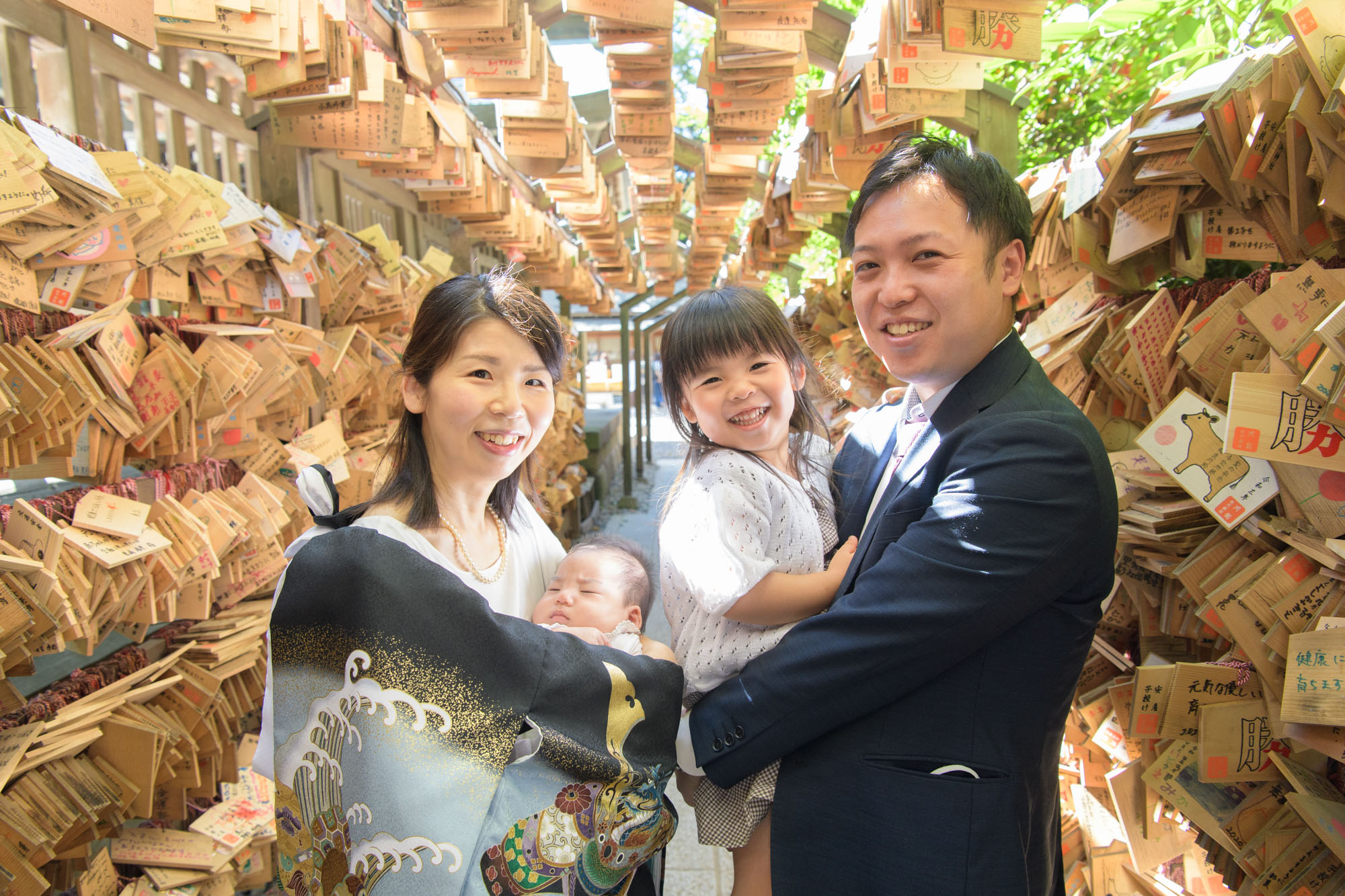 川越氷川神社のお宮参りトンネルの中で、4人で写真を撮る家族