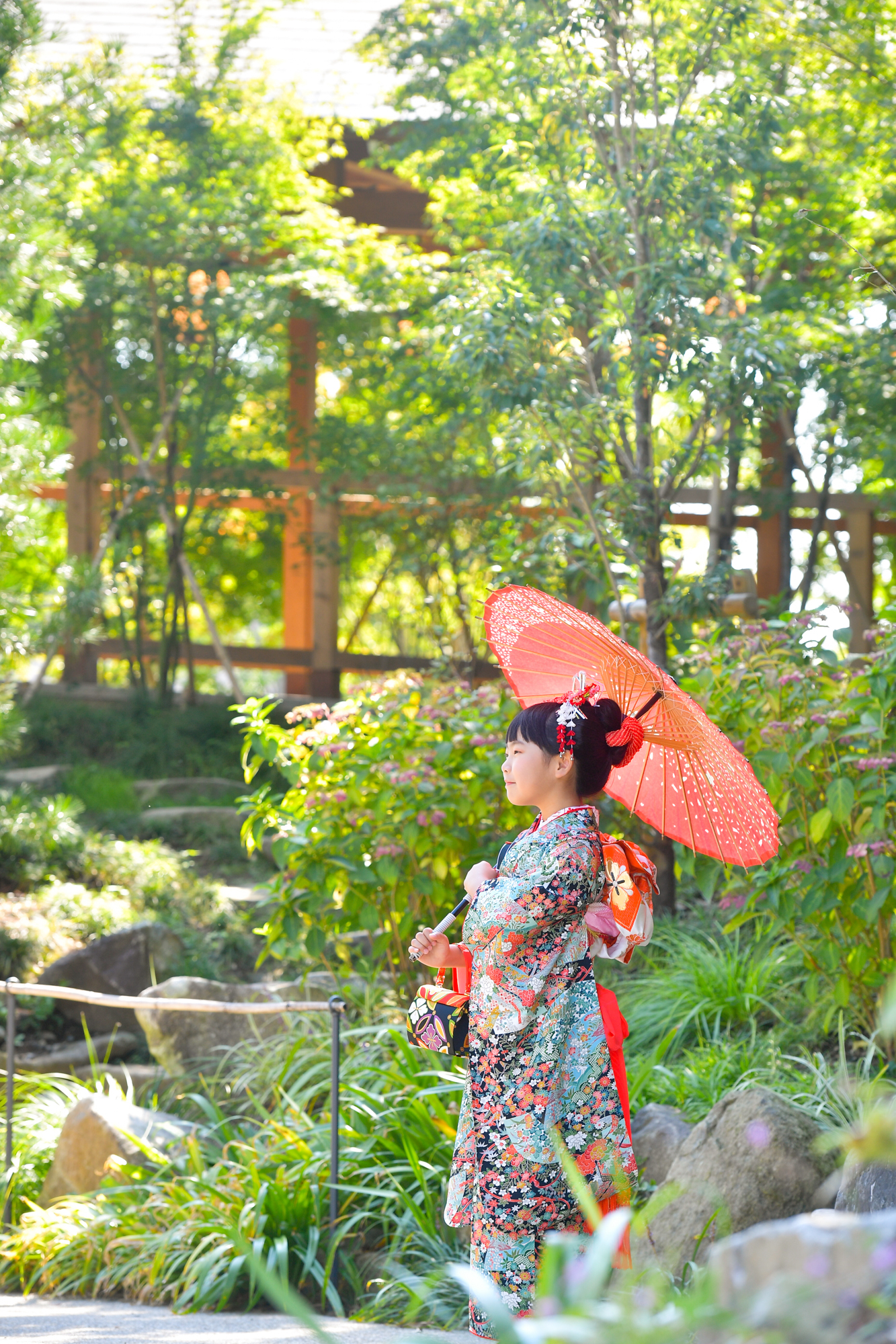 画像 川越氷川神社の境内で赤い和傘をさしてポーズを取る7歳の七五三の女の子