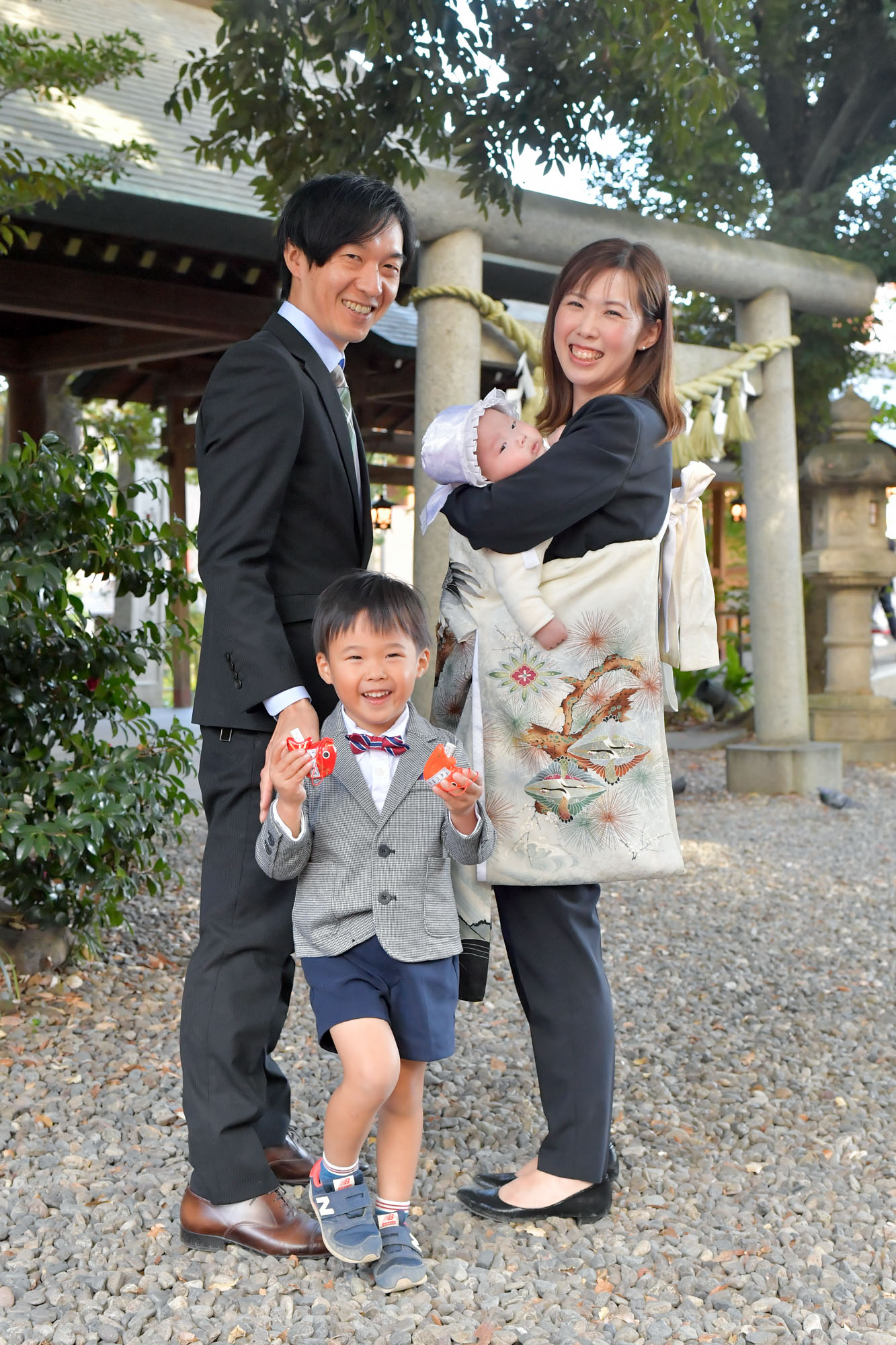 川越氷川神社の石鳥居の前で微笑むお宮参りの家族と5歳の男の子。
