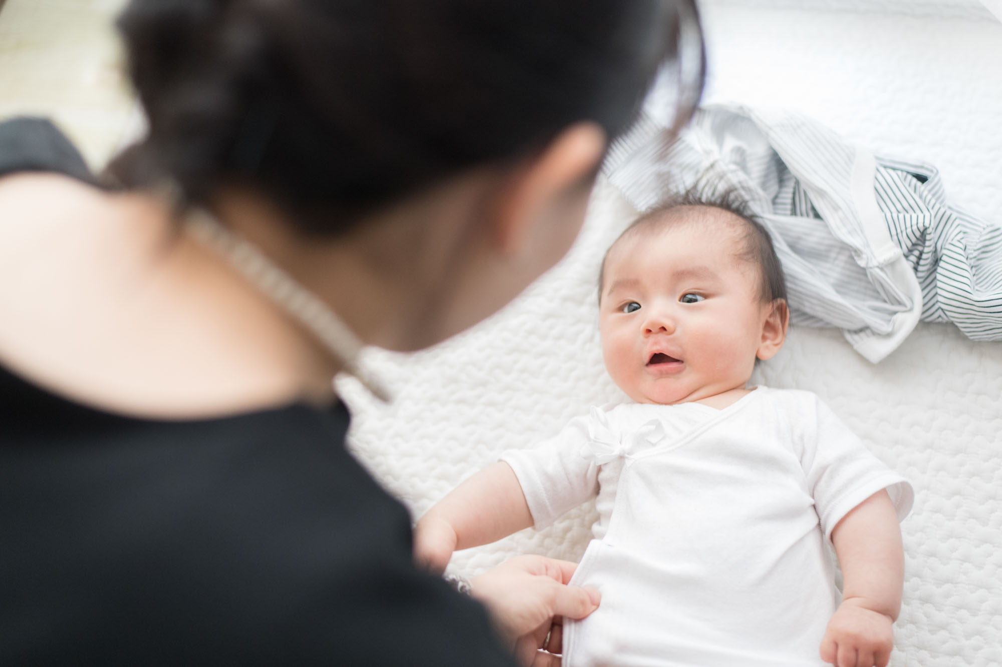 寝かせた赤ちゃんを上からママ