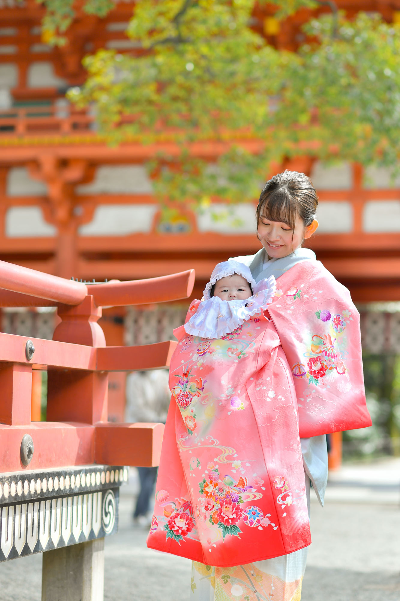 大宮氷川神社のお宮参りでピンクの掛け着姿で赤ちゃんを抱っこする女性
