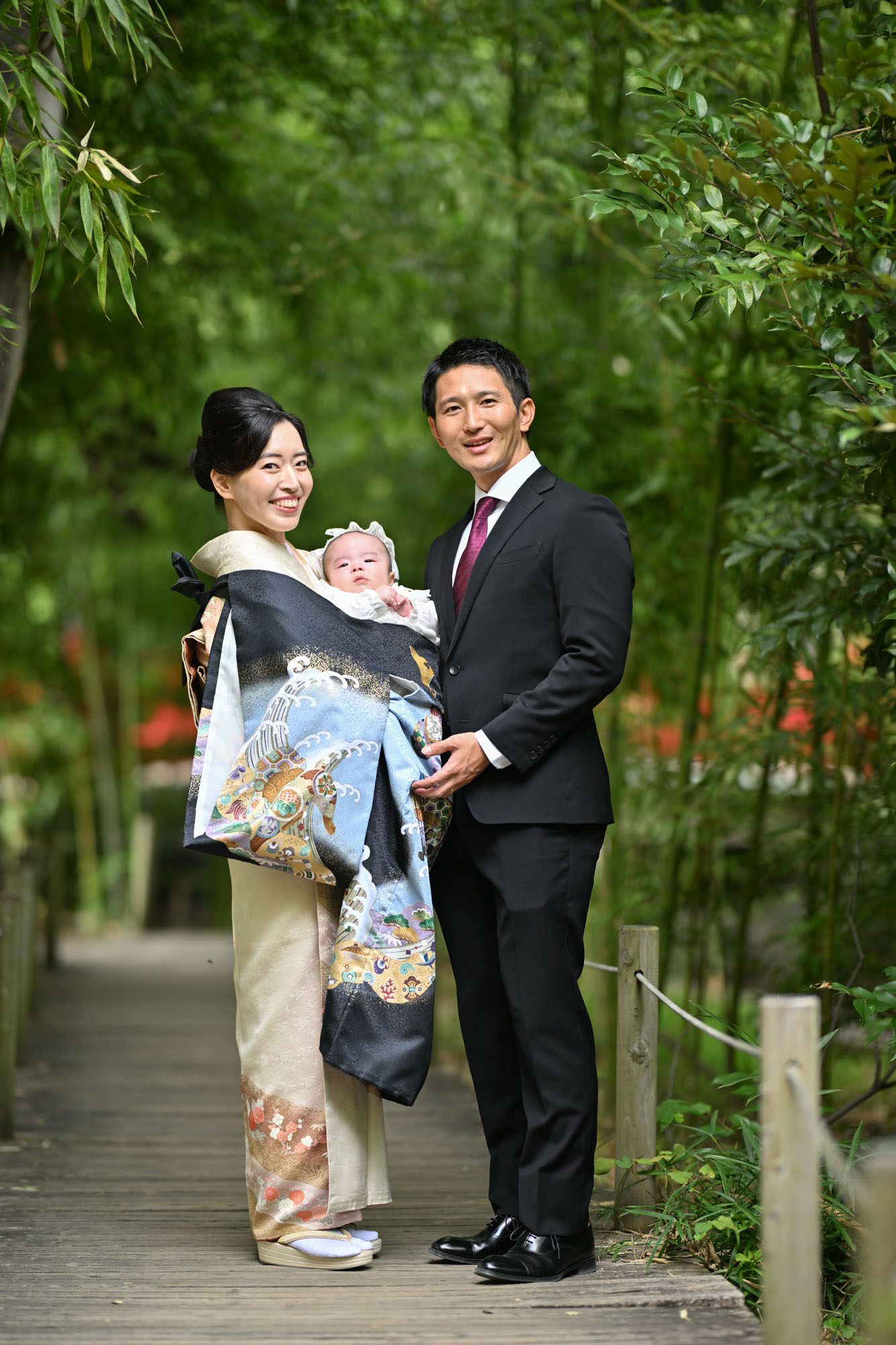 大宮氷川神社のお宮参りで笹の参道で赤ちゃんを抱っこする掛け着姿の女性とパパ