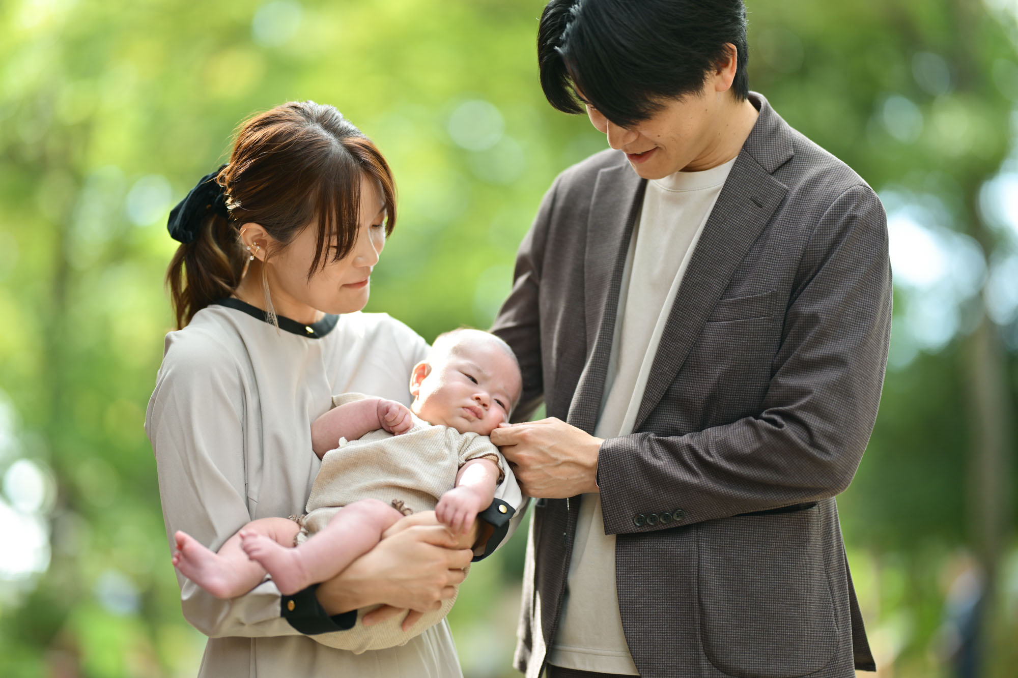 大宮氷川神社のお宮参りで明るい柔らかな光の中赤ちゃんを抱っこするママとパパ